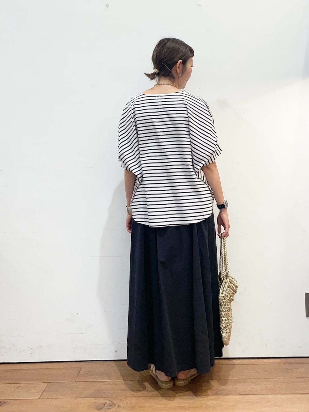 ホワイト系のTシャツ/カットソー、ブラック系のスカート、ホワイト系のサンダルを着用したレディースの夏コーディネートの4枚目の写真
