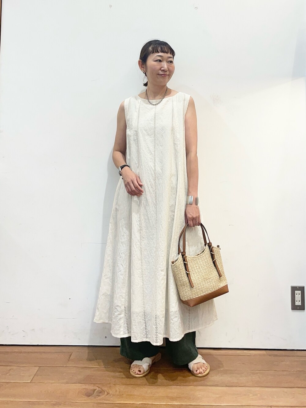 イエロー系のショルダーバッグ、ホワイト系のサンダル、ベージュ系のワンピースを着用したレディースの夏コーディネートの2枚目の写真