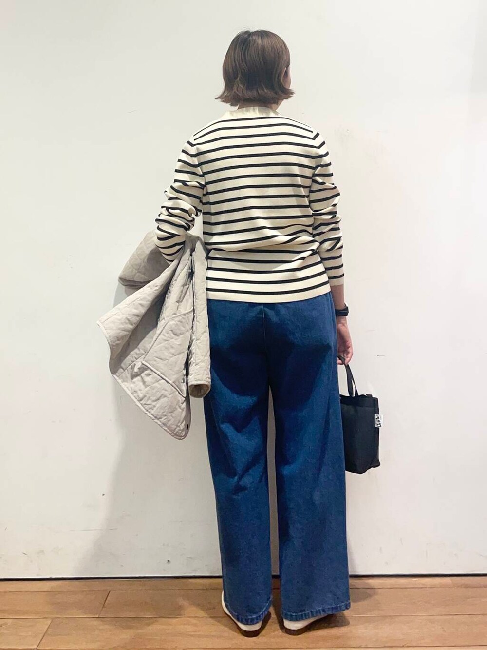 ブルー系のデニムパンツ、グレー系のダウンジャケット/コート、ブラック系のニット/セーターを着用したレディースの春コーディネートの9枚目の写真