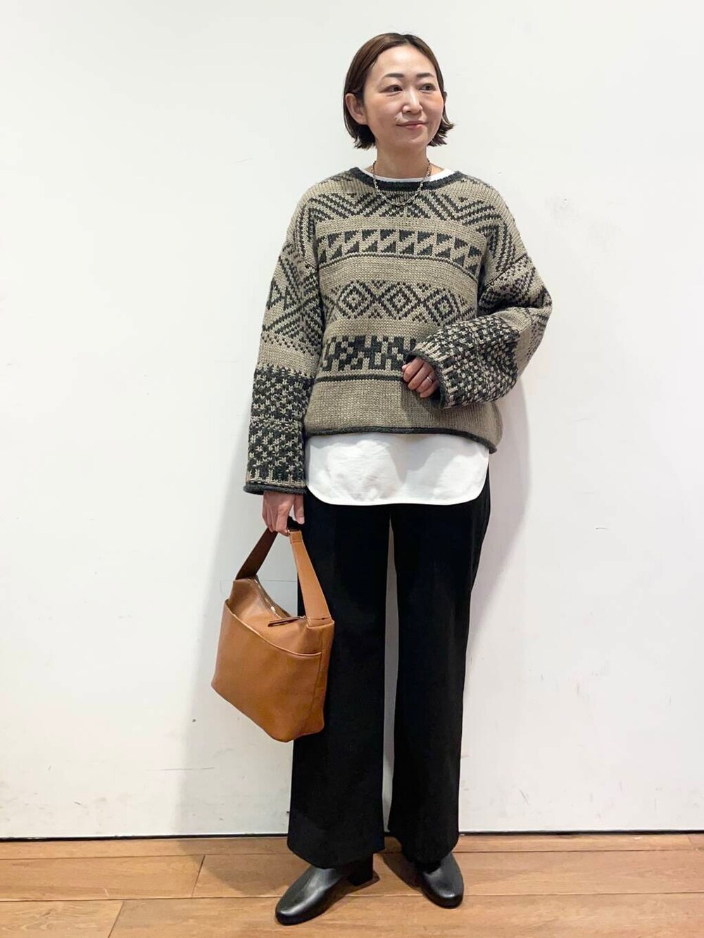 ブラック系のブーツ、イエロー系のショルダーバッグ、ホワイト系のTシャツ/カットソーを着用したレディースの冬コーディネートの2枚目の写真