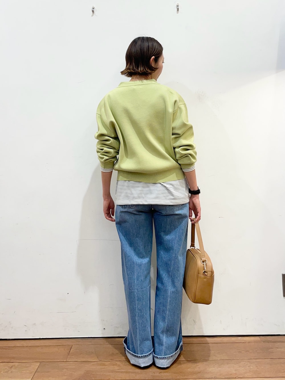 グリーン系のカーディガン/ボレロ、ホワイト系のTシャツ/カットソー、ブルー系のデニムパンツを着用したレディースの冬コーディネートの4枚目の写真