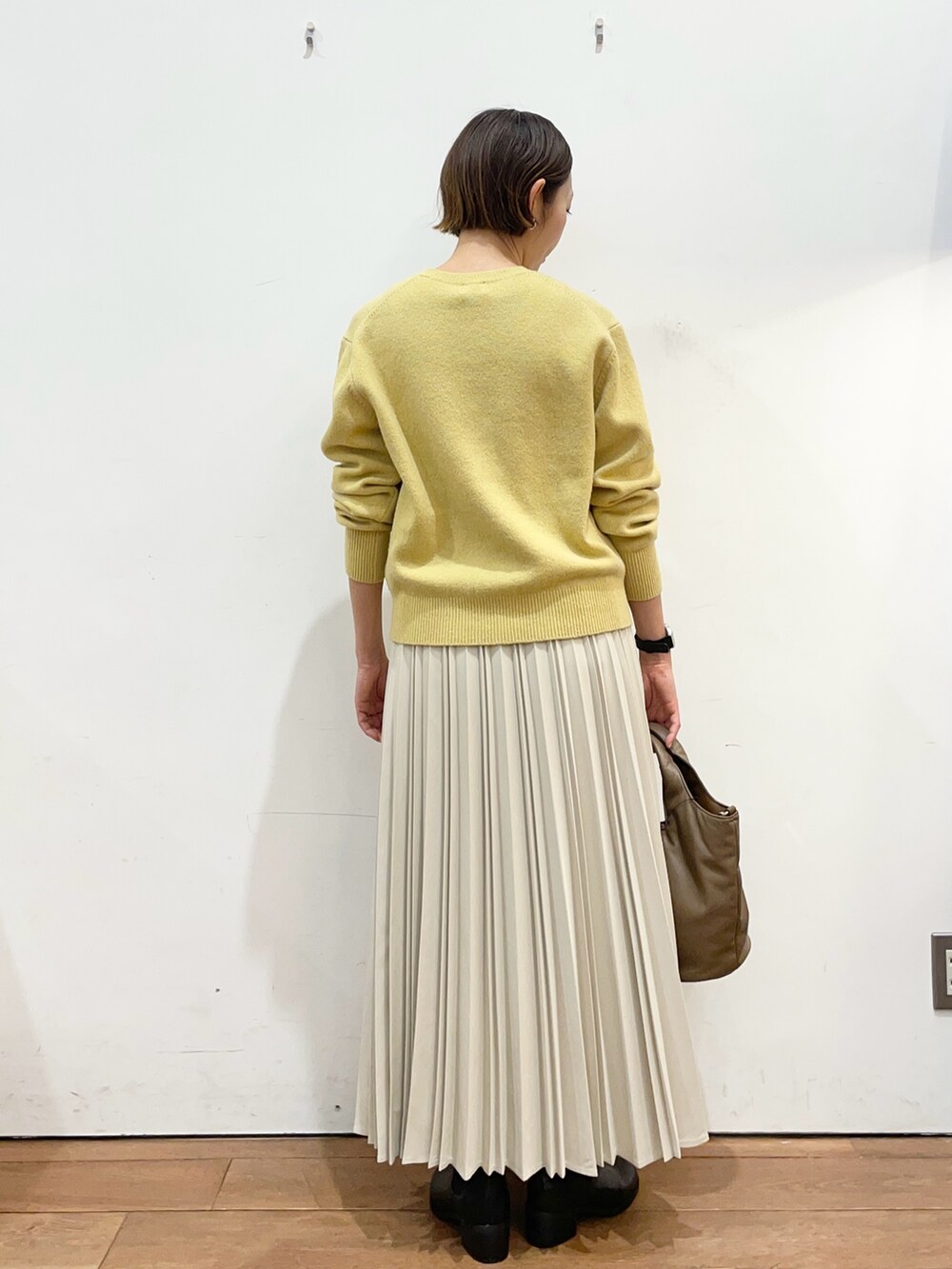 イエロー系のカーディガン/ボレロ、ホワイト系のスカート、ブラック系のブーツを着用したレディースの冬コーディネートの4枚目の写真