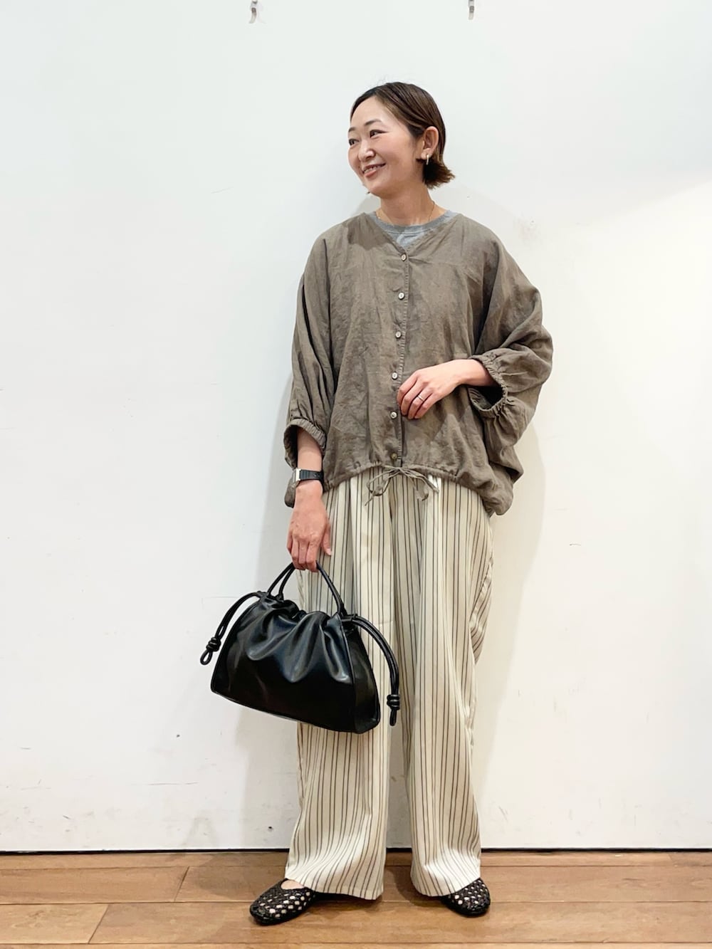 ブラウン系のシャツ/ブラウス、ベージュ系のその他パンツ、ブラック系のトートバッグを着用したレディースの春コーディネートの2枚目の写真
