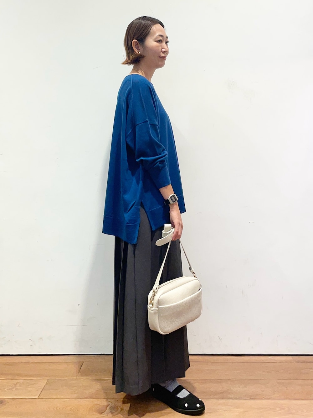 ブルー系のニット/セーター、ブラック系のスニーカー、グレー系のスカートを着用したレディースの秋コーディネートの4枚目の写真