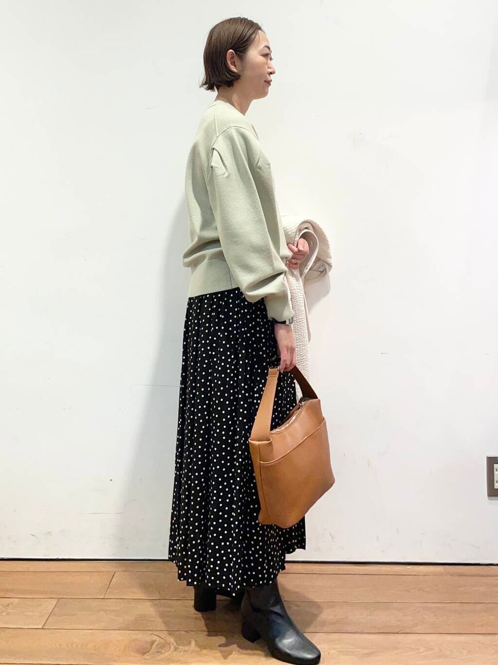 ブラック系のブーツ、ホワイト系のノーカラージャケット、イエロー系のショルダーバッグを着用したレディースの冬コーディネートの8枚目の写真
