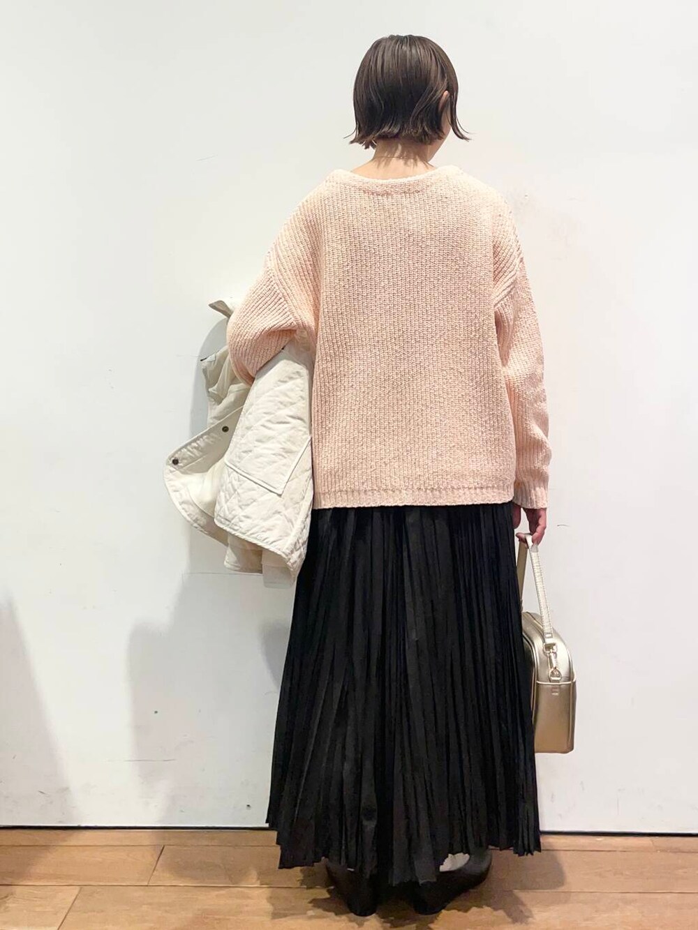 ゴールド系のショルダーバッグ、ブラック系のパンプス、ホワイト系のダウンジャケット/コートを着用したレディースの冬コーディネートの7枚目の写真