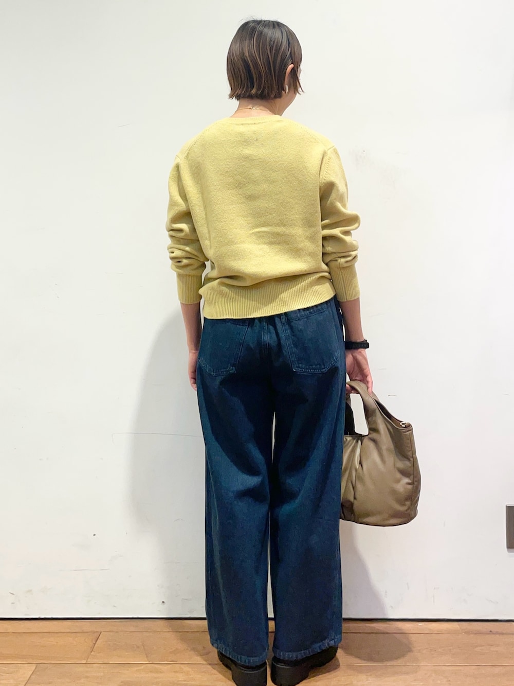 イエロー系のカーディガン/ボレロ、ブルー系のデニムパンツ、ブラウン系のハンドバッグを着用したレディースの秋コーディネートの5枚目の写真
