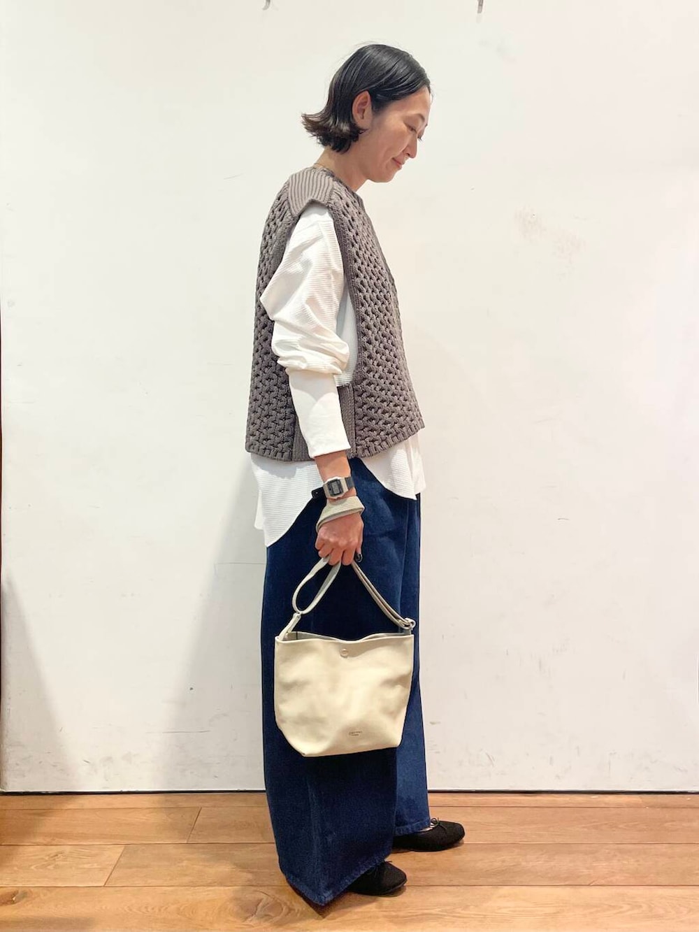 ブラック系のバレエシューズ、ブルー系のデニムパンツ、グレー系のベストを着用したレディースの秋コーディネートの5枚目の写真