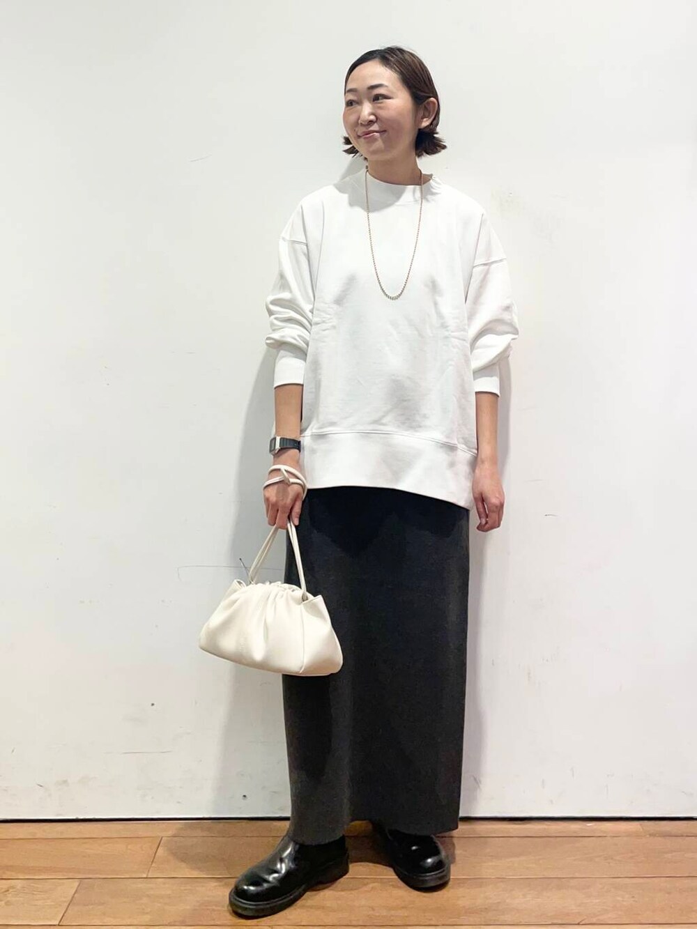 グレー系のスカート、ホワイト系のショルダーバッグ、ホワイト系のTシャツ/カットソーを着用したレディースの冬コーディネートの3枚目の写真