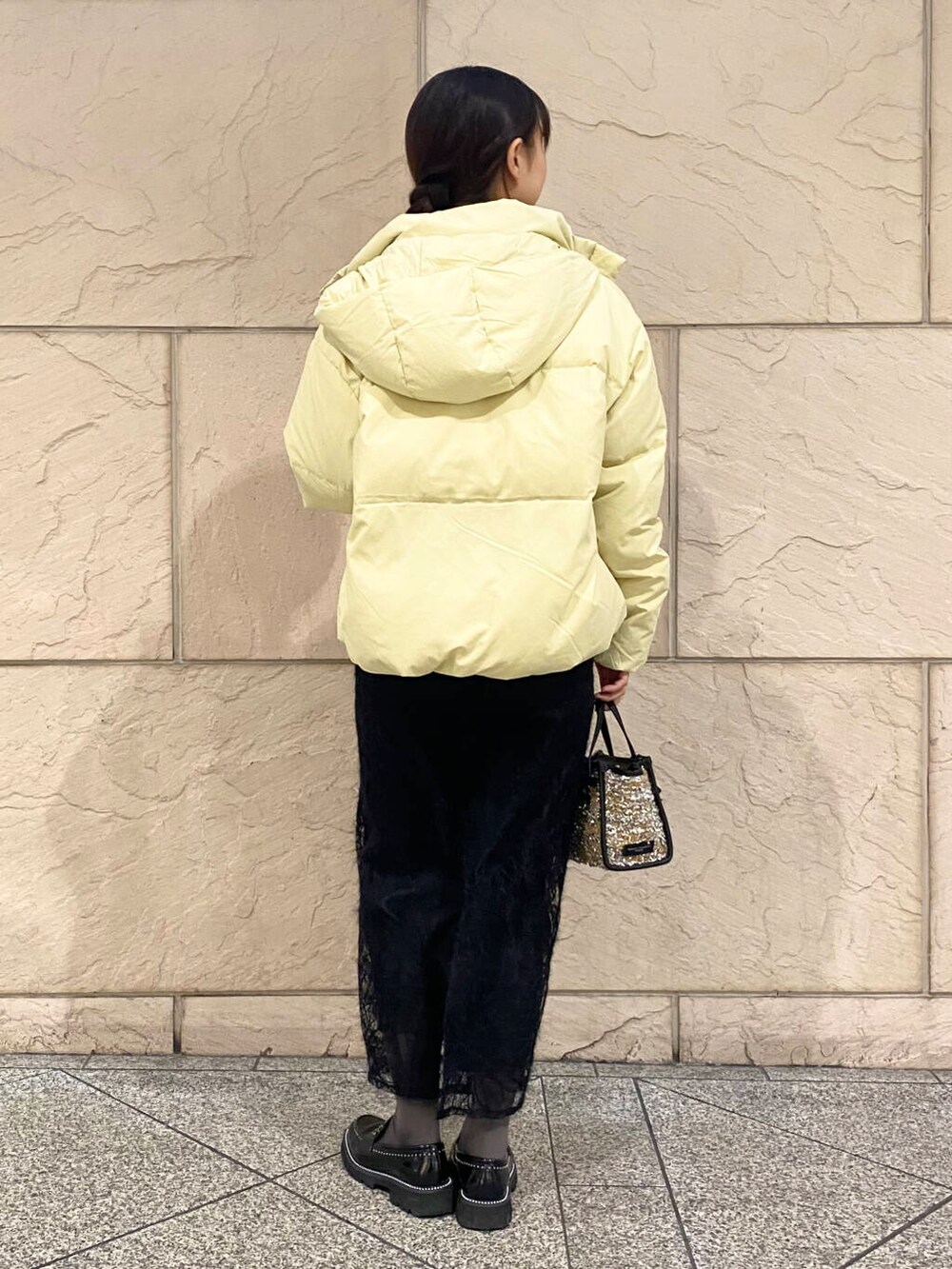 イエロー系のダウンジャケット/コート、グレー系のニット/セーター、イエロー系のハンドバッグを着用したレディースの冬コーディネートの4枚目の写真