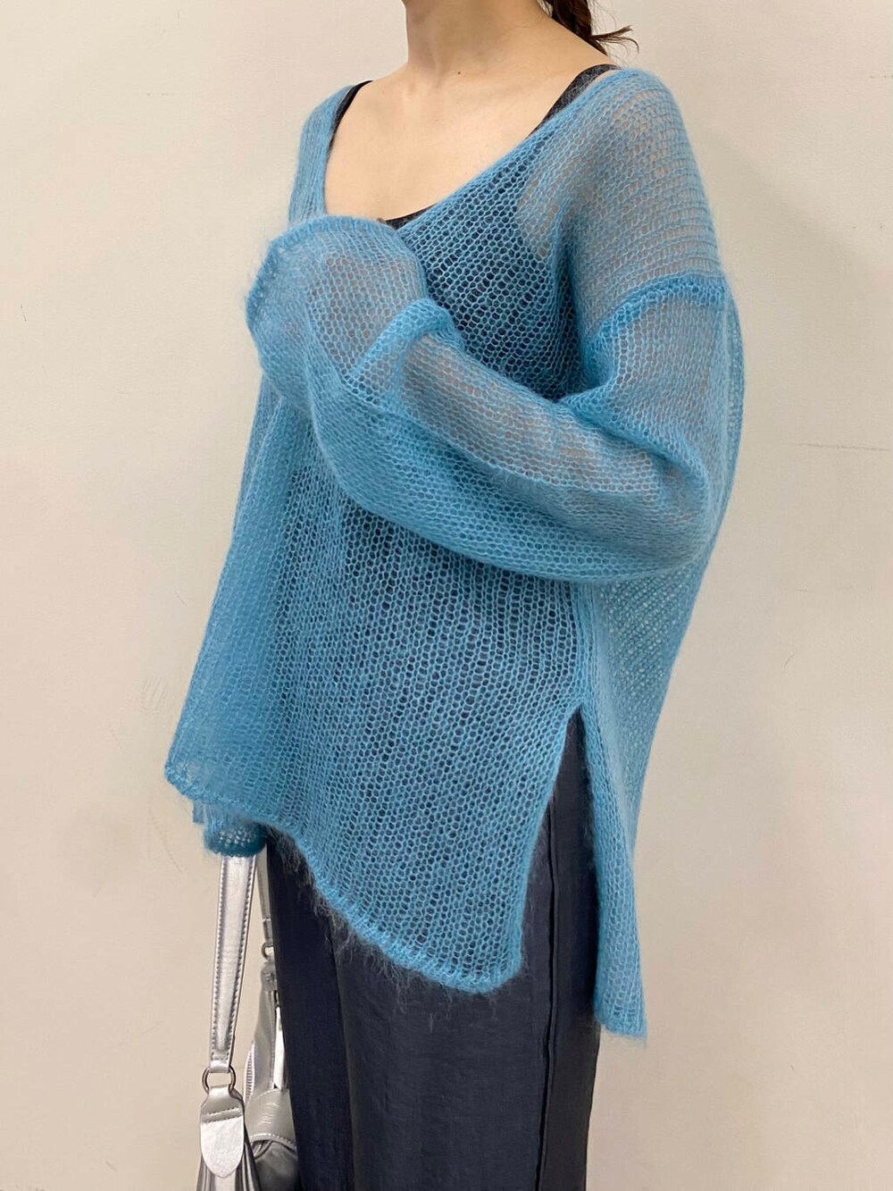 ブルー系のニット/セーター、グレー系のその他パンツ、シルバー系のハンドバッグを着用したレディースの夏コーディネートの6枚目の写真