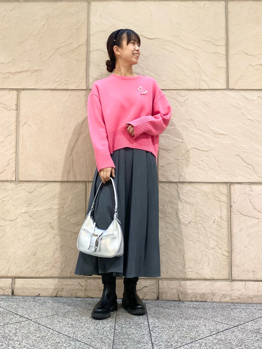 グレー系のスカート、ピンク系のニット/セーター、シルバー系のブローチ/コサージュを着用したレディースの冬コーディネートの5枚目の写真