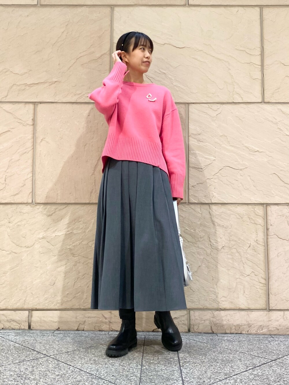 グレー系のスカート、ピンク系のニット/セーター、シルバー系のブローチ/コサージュを着用したレディースの冬コーディネートの3枚目の写真