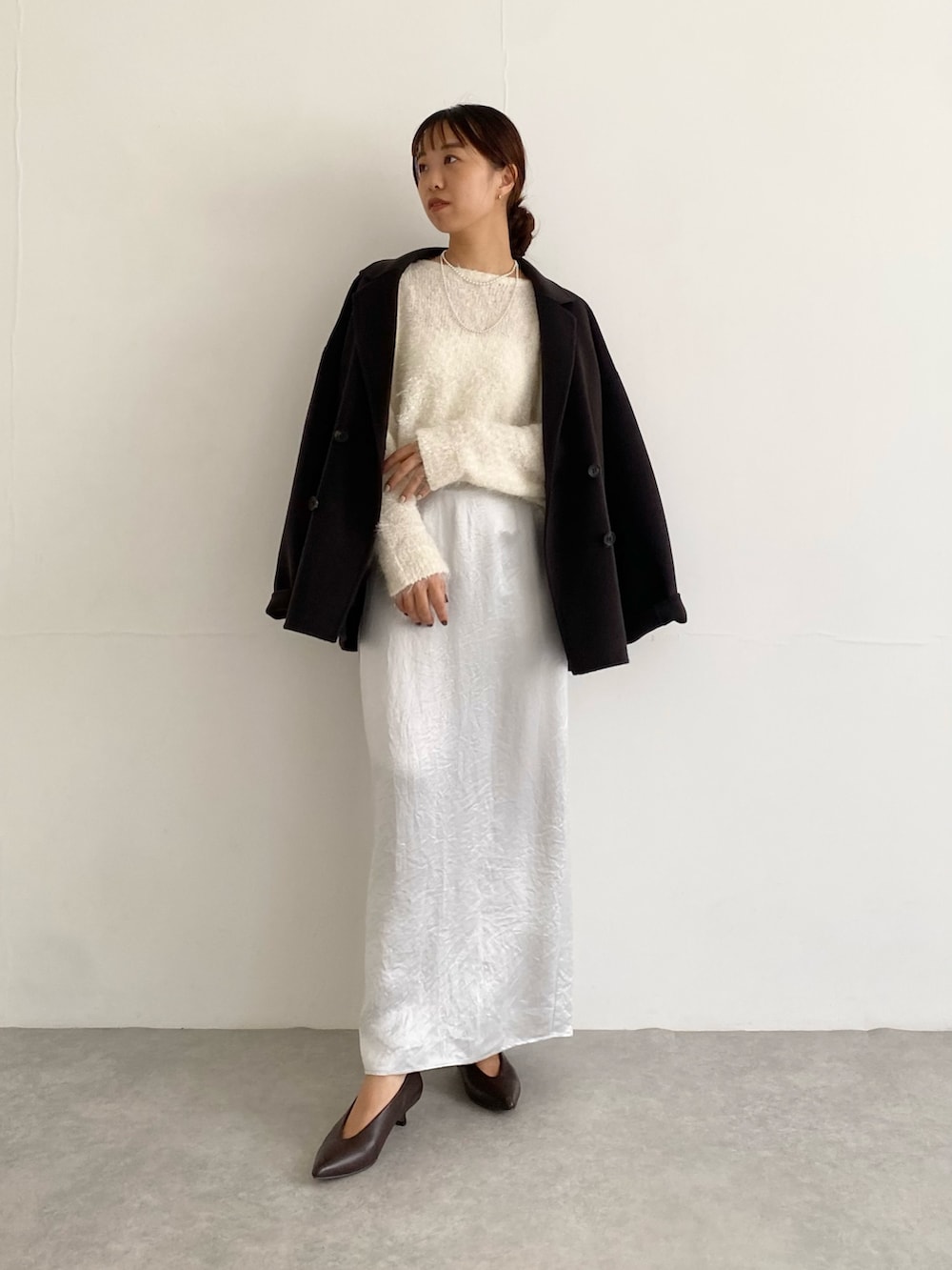 グレー系のその他アウター、ブラウン系のパンプス、ホワイト系のニット/セーターを着用したレディースの秋コーディネートの2枚目の写真