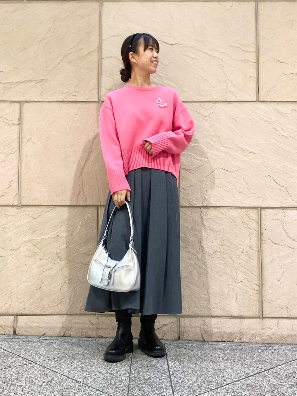 ピンク系のニット/セーター、ブラック系のブーツ、グレー系のスカートを着用したレディースの冬コーディネートの5枚目の写真