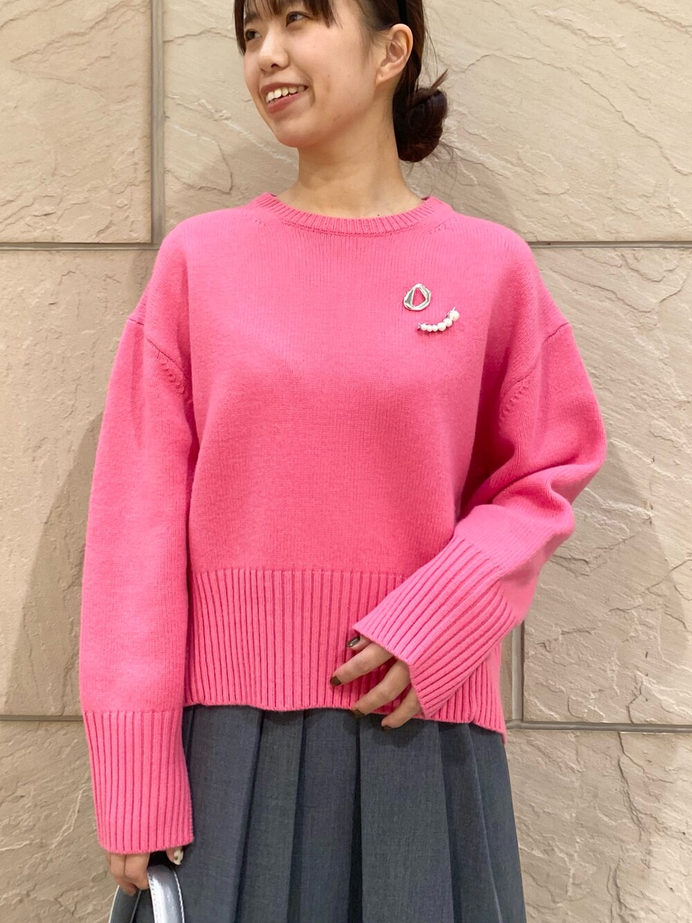 グレー系のスカート、ピンク系のニット/セーター、シルバー系のブローチ/コサージュを着用したレディースの冬コーディネートの8枚目の写真