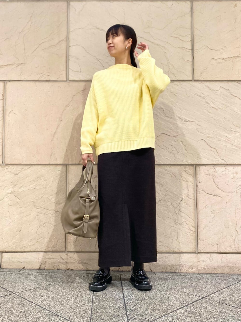 ベージュ系のボストンバッグ、グレー系のスカート、イエロー系のニット/セーターを着用したレディースの冬コーディネートの2枚目の写真