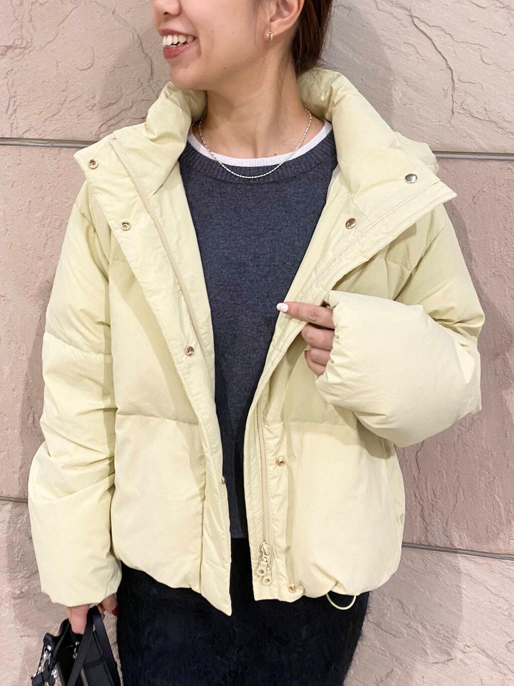 イエロー系のダウンジャケット/コート、グレー系のニット/セーター、イエロー系のハンドバッグを着用したレディースの冬コーディネートの5枚目の写真