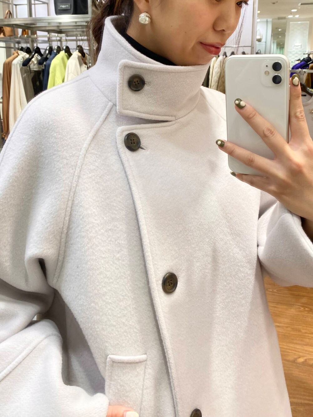 グレー系のピーコート、ブラック系のブーツ、グレー系のスカートを着用したレディースの秋コーディネートの2枚目の写真