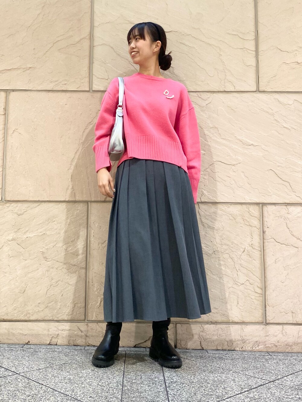 グレー系のスカート、ピンク系のニット/セーター、シルバー系のブローチ/コサージュを着用したレディースの冬コーディネートの2枚目の写真