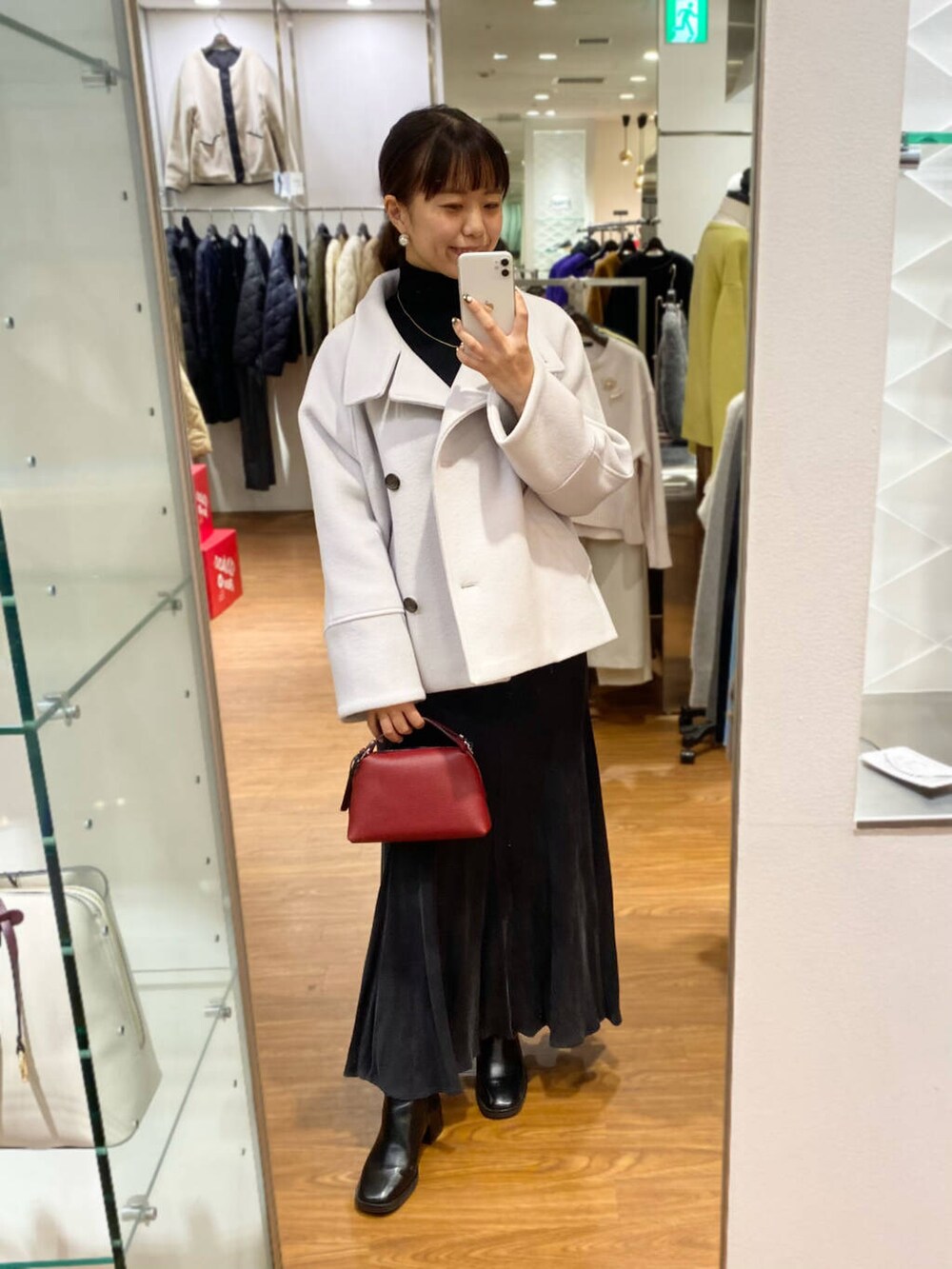 グレー系のピーコート、ブラック系のブーツ、グレー系のスカートを着用したレディースの秋コーディネートの4枚目の写真