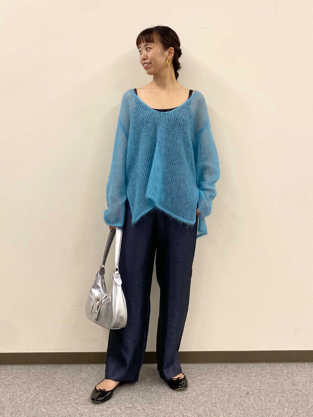 ブルー系のニット/セーター、グレー系のその他パンツ、シルバー系のハンドバッグを着用したレディースの夏コーディネートの2枚目の写真