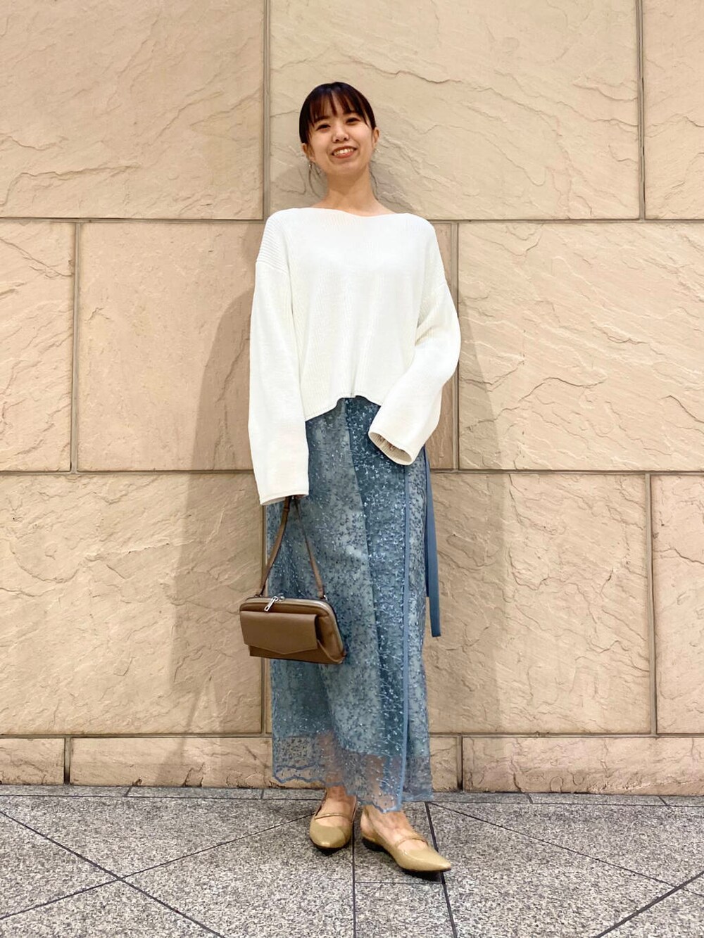 ベージュ系のパンプス、ブルー系のスカート、ホワイト系のニット/セーターを着用したレディースの冬コーディネートの2枚目の写真