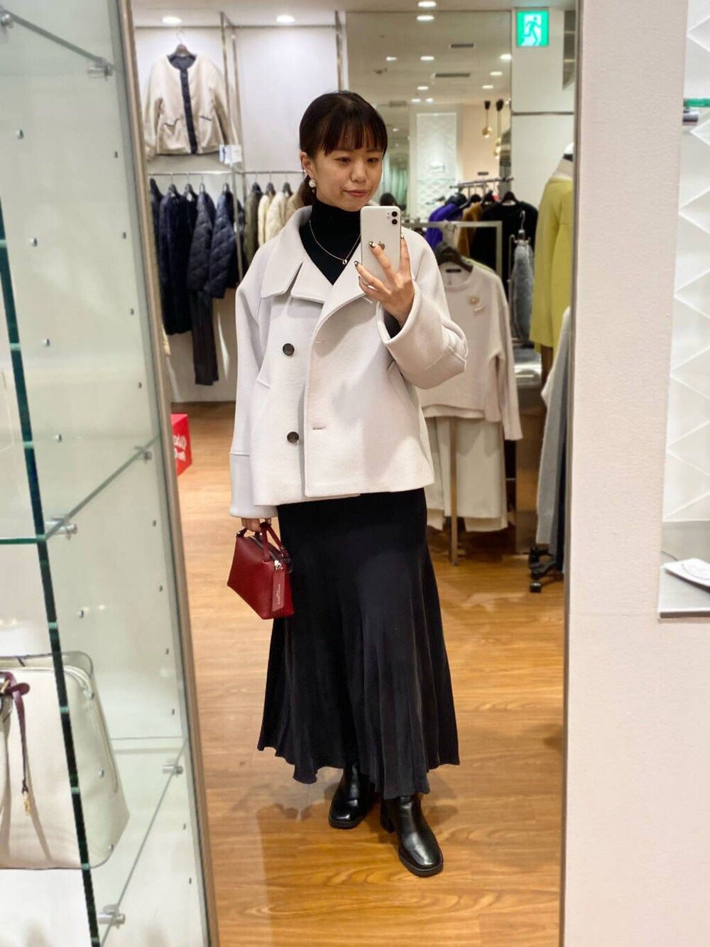 グレー系のピーコート、ブラック系のブーツ、グレー系のスカートを着用したレディースの秋コーディネートの3枚目の写真