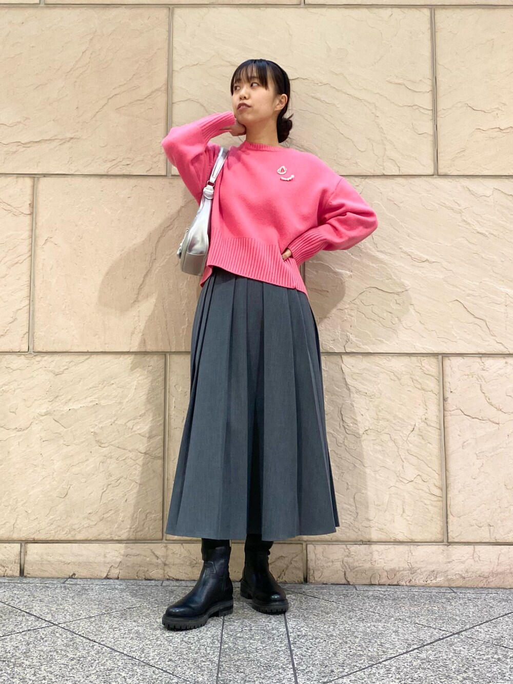 グレー系のスカート、ピンク系のニット/セーター、シルバー系のブローチ/コサージュを着用したレディースの冬コーディネートの4枚目の写真