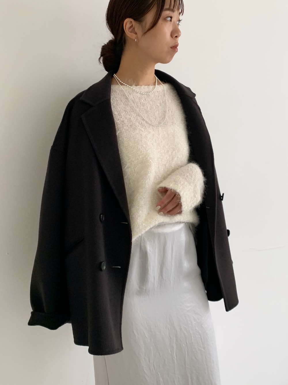 グレー系のその他アウター、ブラウン系のパンプス、ホワイト系のニット/セーターを着用したレディースの秋コーディネートの5枚目の写真