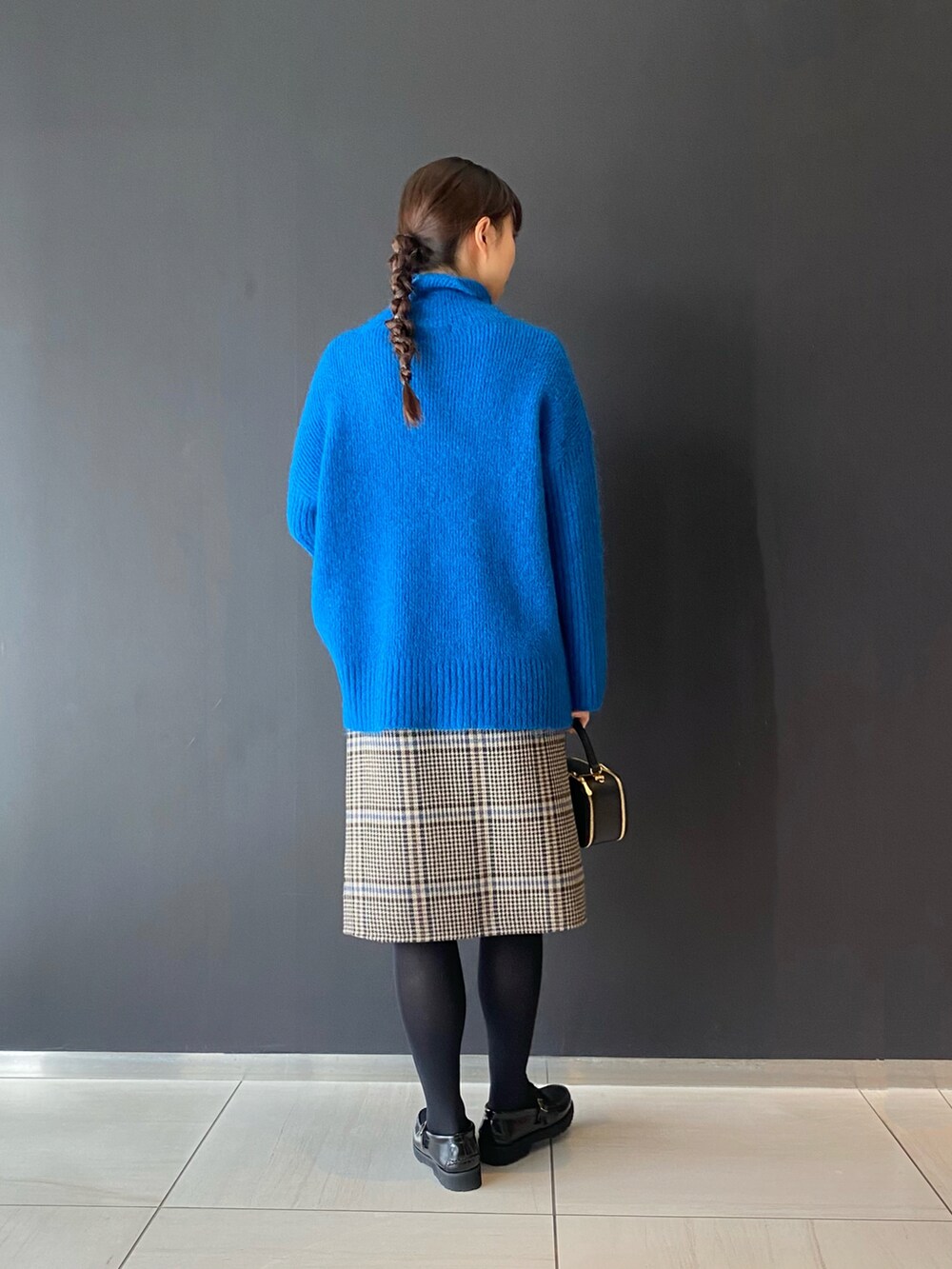ブルー系のニット/セーター、ブルー系のスカート、ブラック系のショルダーバッグを着用したレディースの冬コーディネートの2枚目の写真