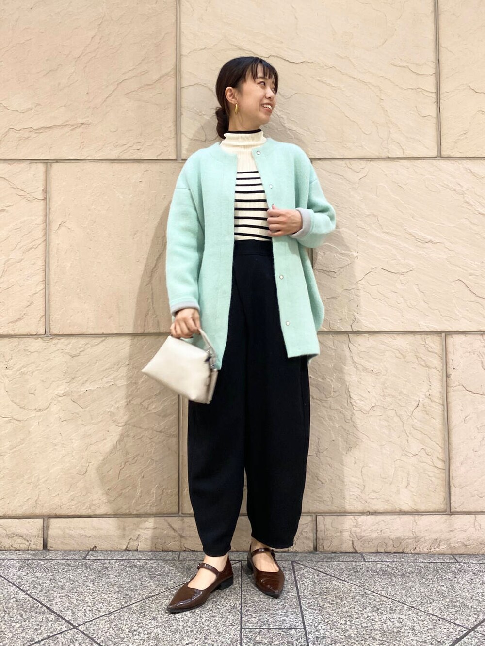 ブラック系のその他パンツ、ホワイト系のニット/セーター、グリーン系のカーディガン/ボレロを着用したレディースの秋コーディネートの3枚目の写真