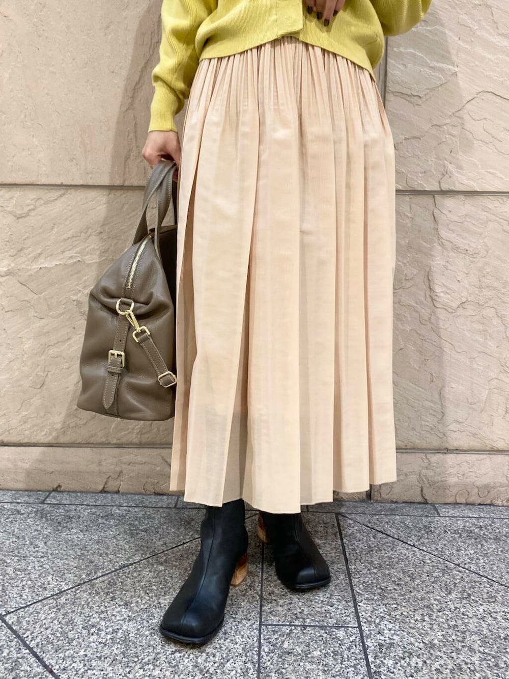 ベージュ系のボストンバッグ、イエロー系のスカート、イエロー系のカーディガン/ボレロを着用したレディースの冬コーディネートの7枚目の写真