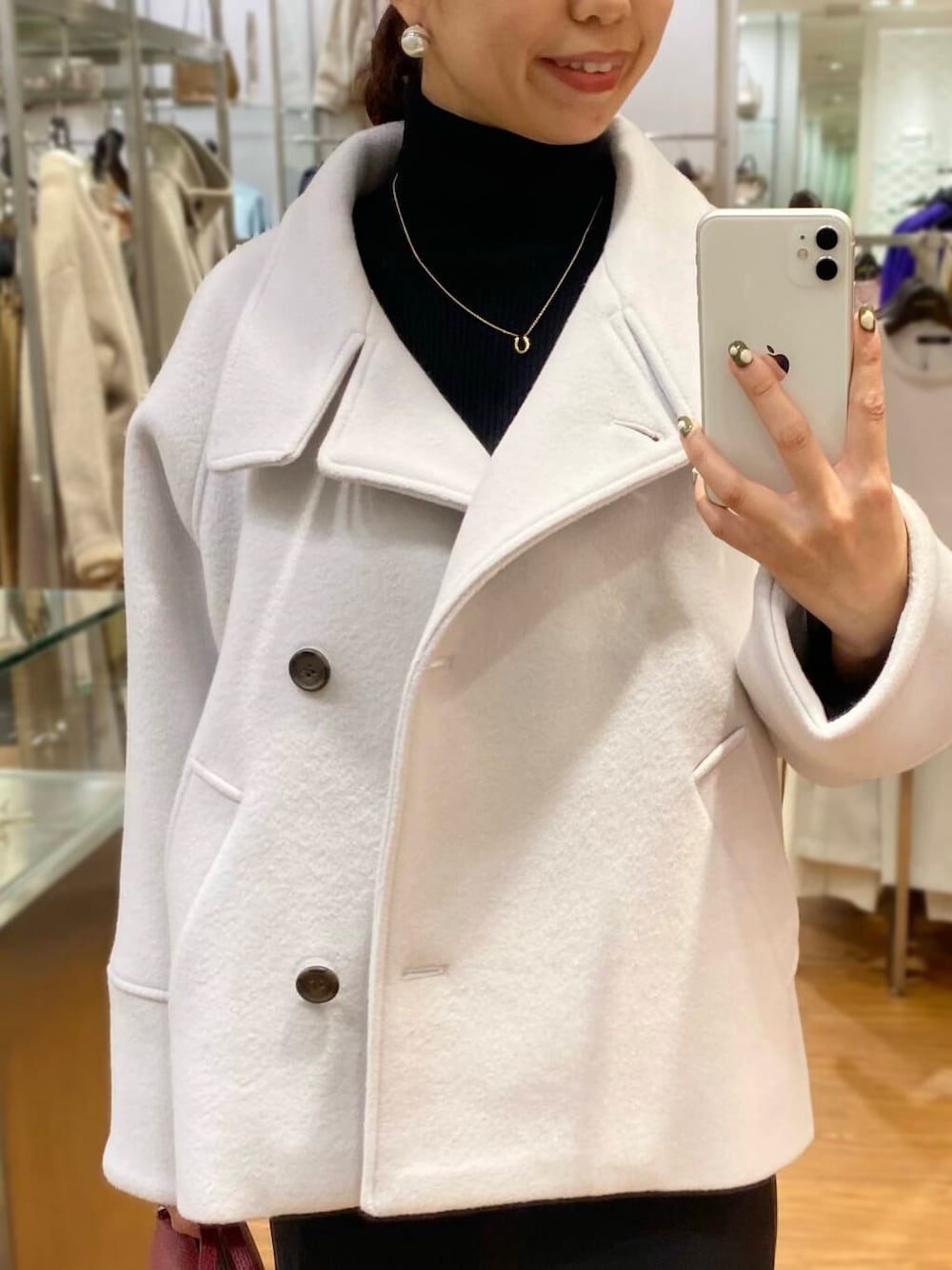 グレー系のピーコート、ブラック系のブーツ、グレー系のスカートを着用したレディースの秋コーディネートの5枚目の写真