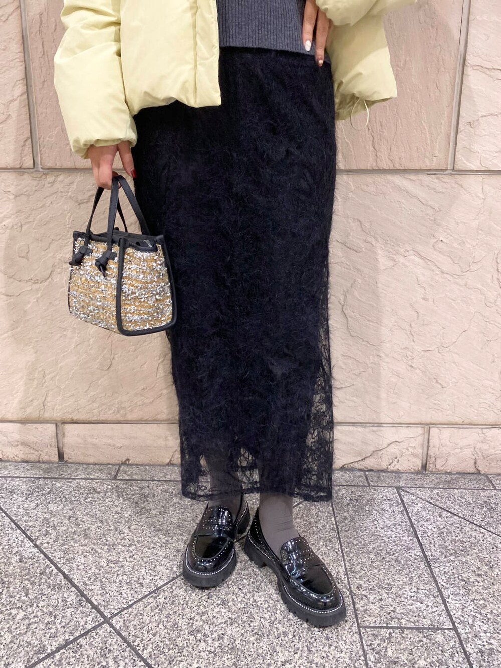 イエロー系のダウンジャケット/コート、グレー系のニット/セーター、イエロー系のハンドバッグを着用したレディースの冬コーディネートの6枚目の写真