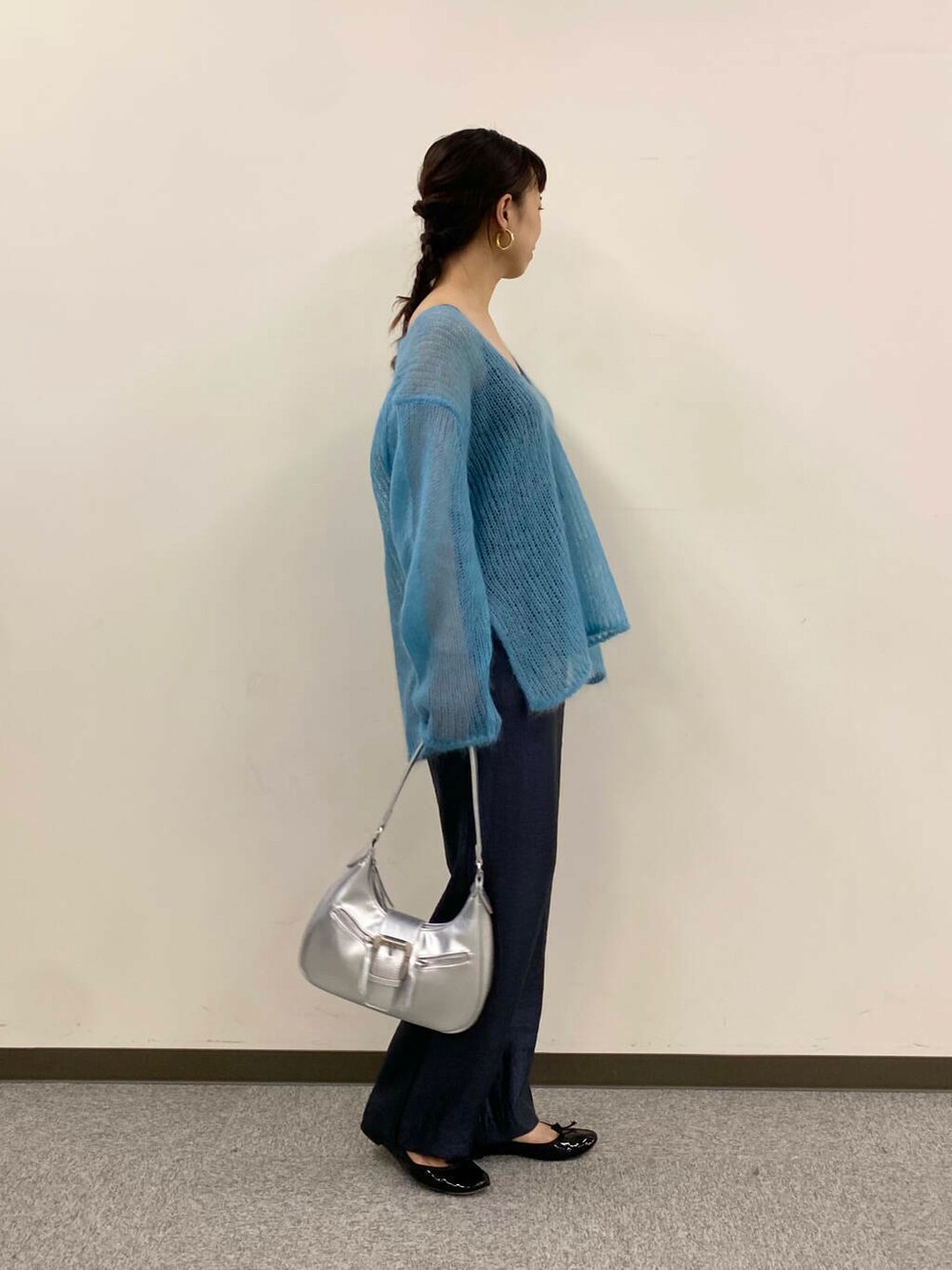 ブルー系のニット/セーター、グレー系のその他パンツ、シルバー系のハンドバッグを着用したレディースの夏コーディネートの3枚目の写真