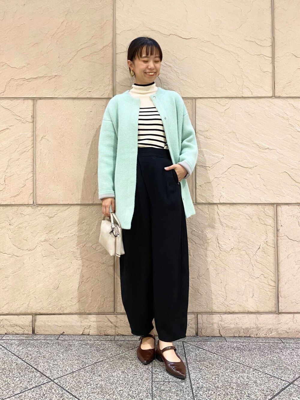 ブラック系のその他パンツ、ホワイト系のニット/セーター、グリーン系のカーディガン/ボレロを着用したレディースの秋コーディネートの4枚目の写真