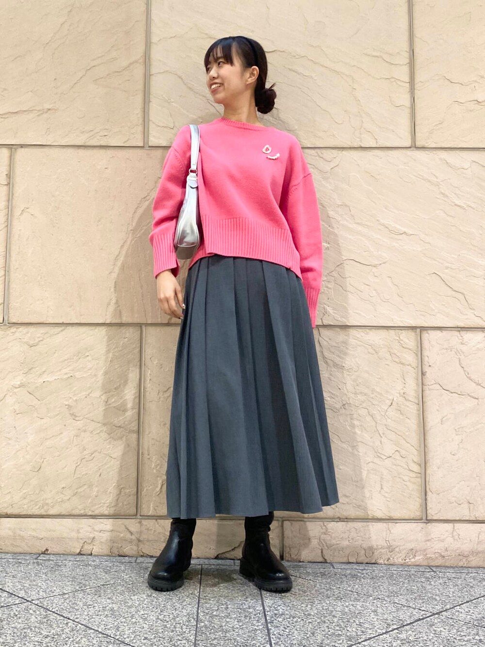 ピンク系のニット/セーター、ブラック系のブーツ、グレー系のスカートを着用したレディースの冬コーディネートの2枚目の写真
