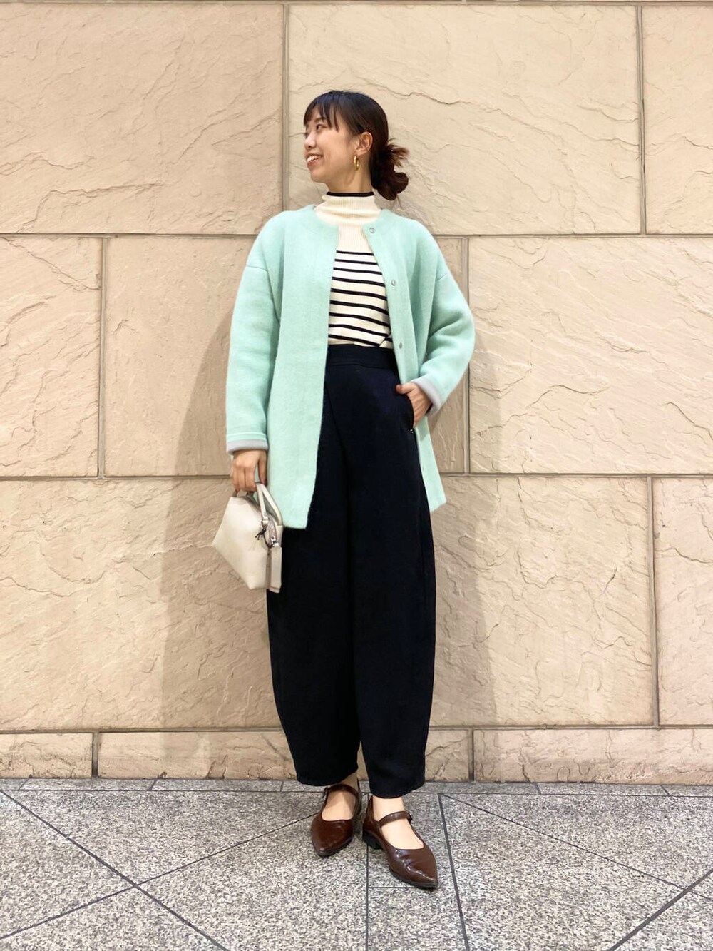 ブラック系のその他パンツ、ホワイト系のニット/セーター、グリーン系のカーディガン/ボレロを着用したレディースの秋コーディネートの2枚目の写真