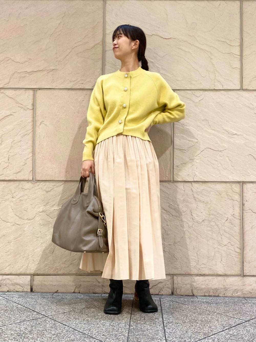 ベージュ系のボストンバッグ、イエロー系のスカート、イエロー系のカーディガン/ボレロを着用したレディースの冬コーディネートの3枚目の写真