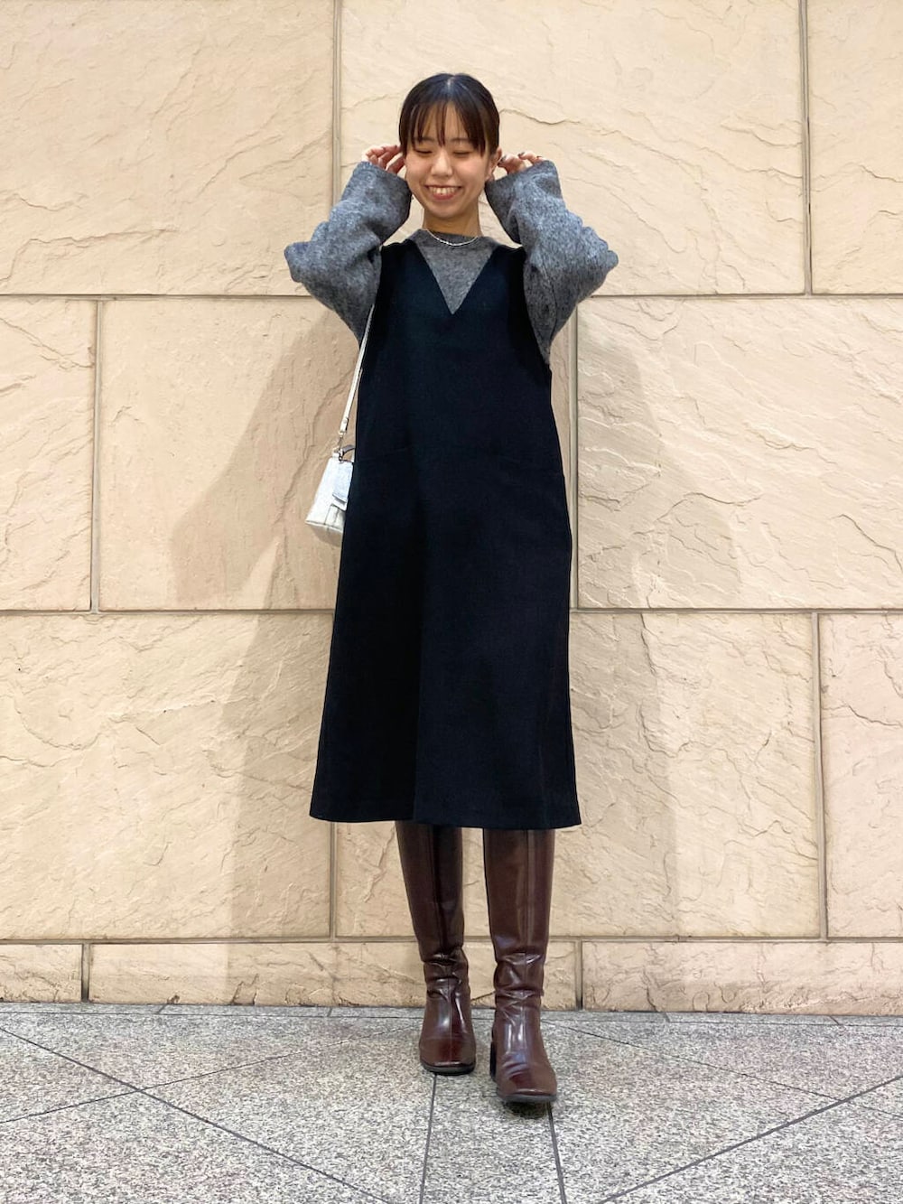 レッド系のブーツ、ブラック系のワンピース、グレー系のニット/セーターを着用したレディースの冬コーディネートの2枚目の写真