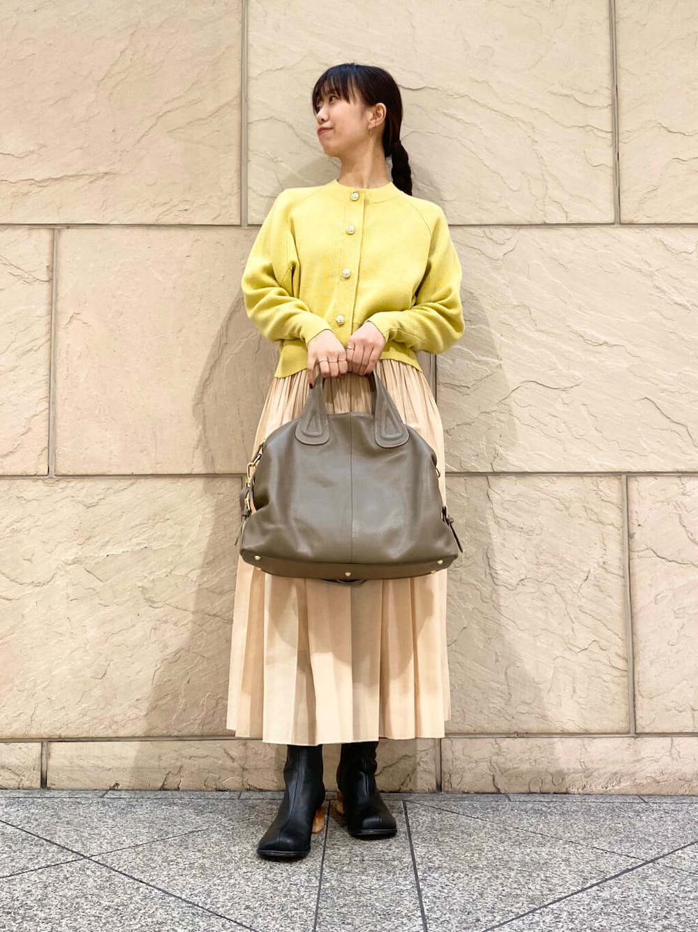ベージュ系のボストンバッグ、イエロー系のスカート、イエロー系のカーディガン/ボレロを着用したレディースの冬コーディネートの2枚目の写真