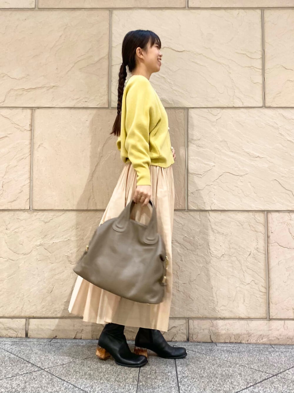 ベージュ系のボストンバッグ、イエロー系のスカート、イエロー系のカーディガン/ボレロを着用したレディースの冬コーディネートの4枚目の写真