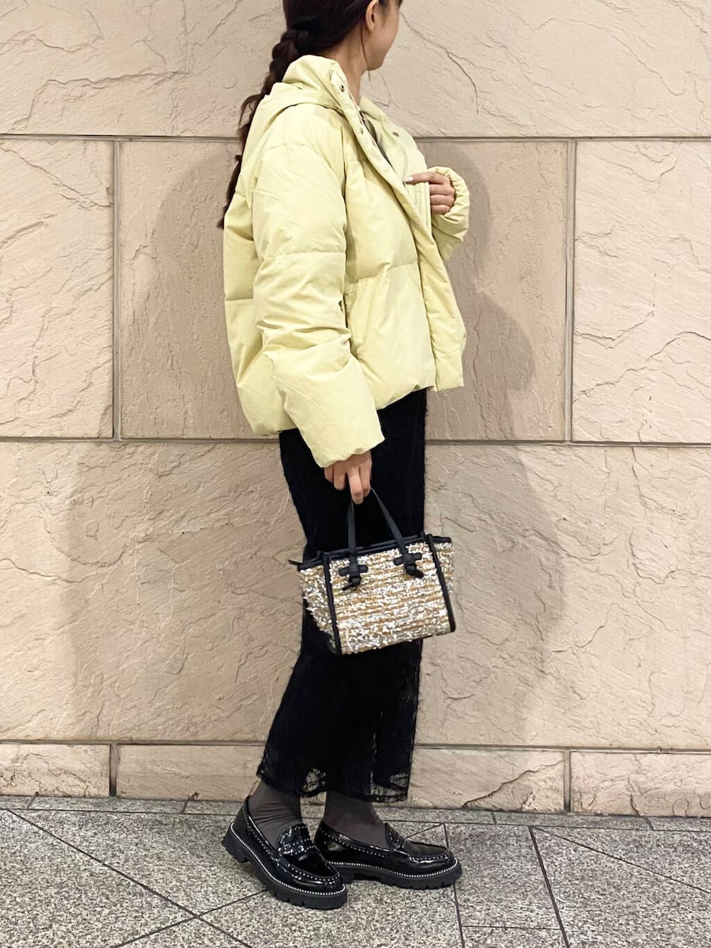 イエロー系のダウンジャケット/コート、グレー系のニット/セーター、イエロー系のハンドバッグを着用したレディースの冬コーディネートの3枚目の写真