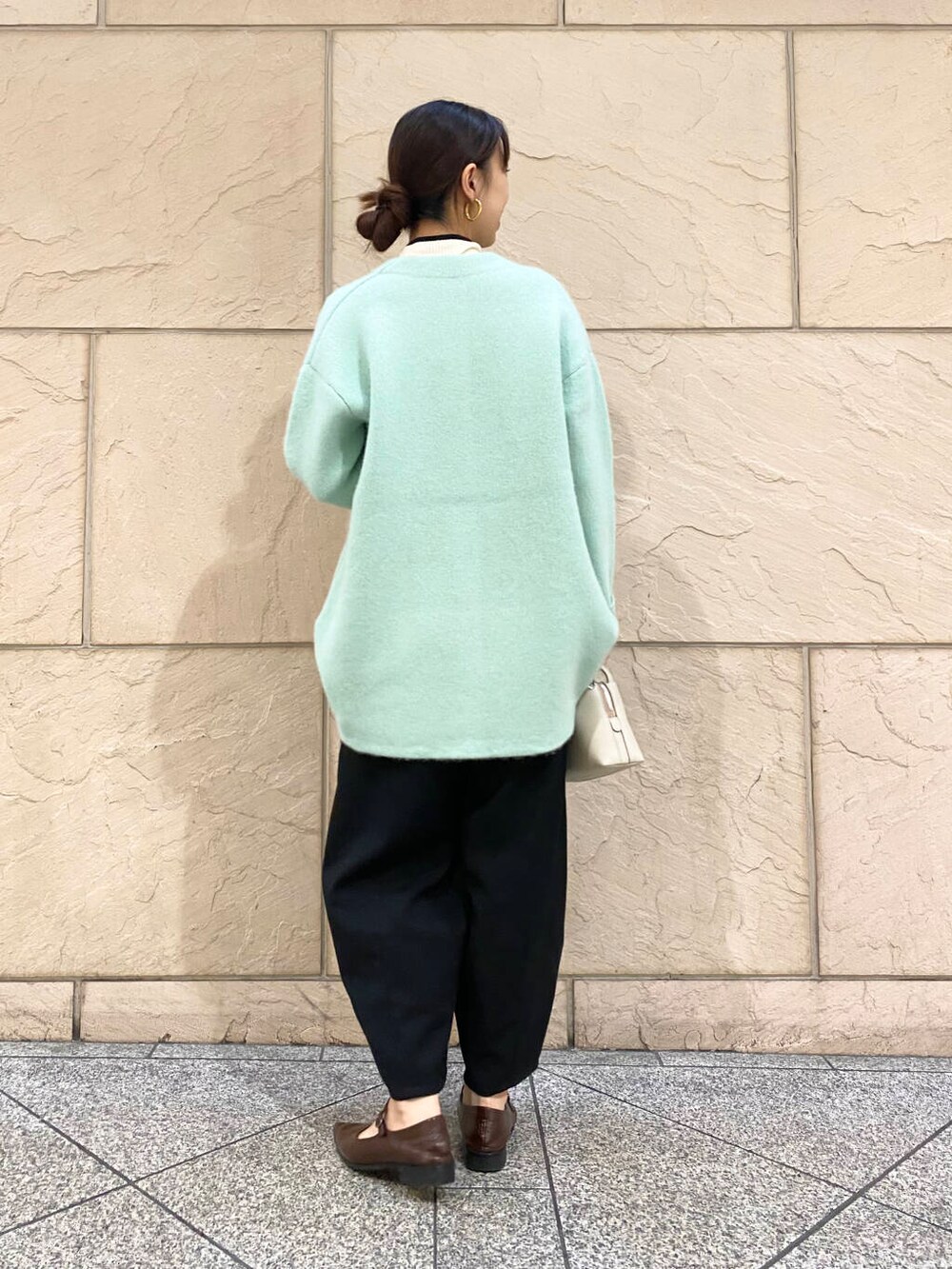 ブラック系のその他パンツ、ホワイト系のニット/セーター、グリーン系のカーディガン/ボレロを着用したレディースの秋コーディネートの6枚目の写真