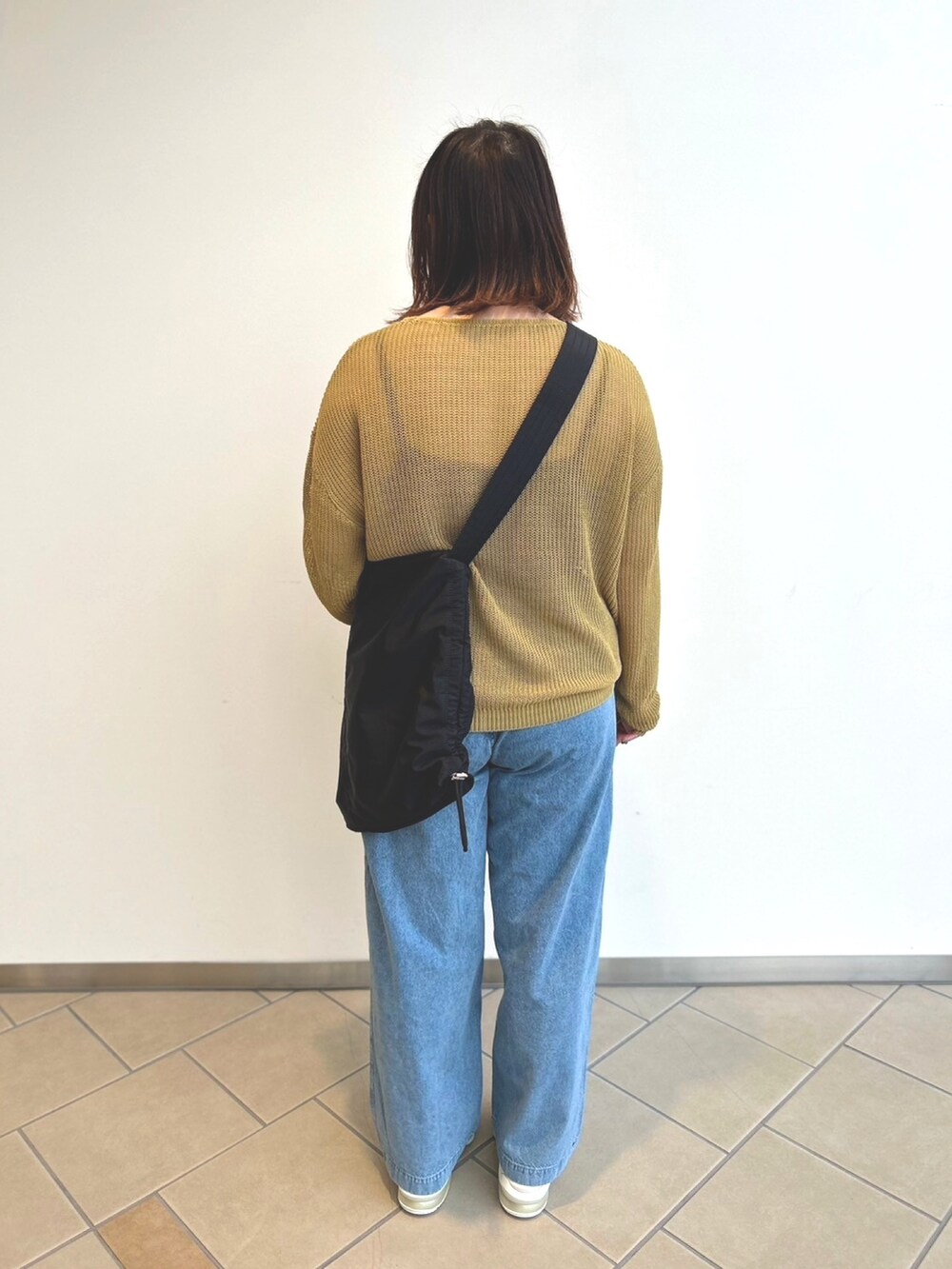 ブルー系のデニムパンツ、イエロー系のニット/セーター、ブラック系のキャミソールを着用したレディースの春コーディネートの3枚目の写真