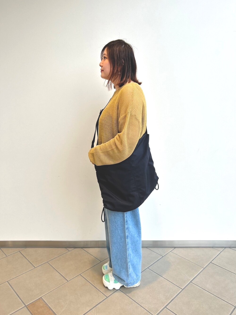 ブルー系のデニムパンツ、イエロー系のニット/セーター、ブラック系のキャミソールを着用したレディースの春コーディネートの2枚目の写真