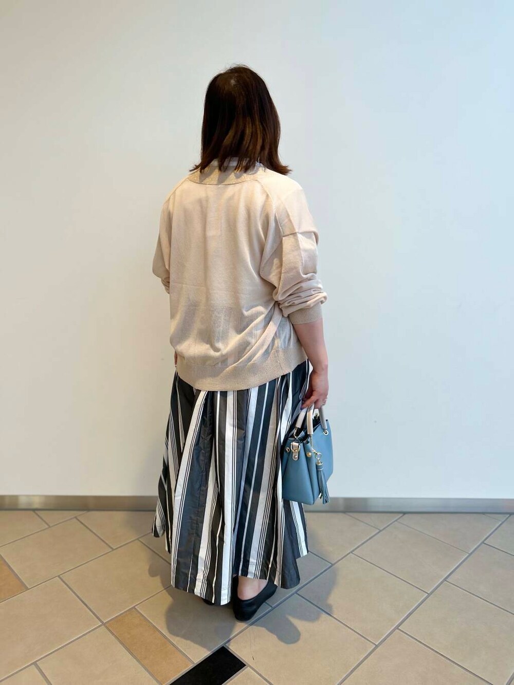 ブルー系のトートバッグ、ホワイト系のTシャツ/カットソー、ホワイト系のスカートを着用したレディースの夏コーディネートの2枚目の写真