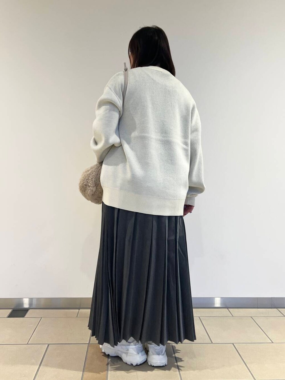ベージュ系のショルダーバッグ、ホワイト系のニット/セーター、グレー系のスカートを着用したレディースの秋コーディネートの3枚目の写真