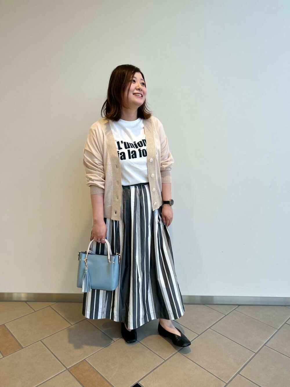 ブルー系のトートバッグ、ホワイト系のTシャツ/カットソー、ホワイト系のスカートを着用したレディースの夏コーディネートの3枚目の写真